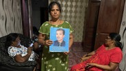 Eine Frau in Sri Lanka hält das Bild ihres vermissten Ehemanns hoch. © NDR Foto: Charlotte Horn