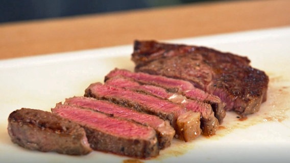 Ein in Streifen geschnittenes Steak liegt auf einem Küchenbrett. © NDR 
