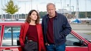 Mila Sahin (Almila Bagriacik), Klaus Borowski (Axel Milberg) stehen vor einem roten Auto. © NDR Foto: Christine Schroeder