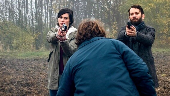 Die Kommissare Lessing (Christian Ulmen) und Kira Dorn (Nora Tschirner) zielen mit Waffen auf einen Mann.  