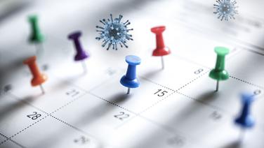 Corona-Viren schweben über einem Kalender. Symbolbild © fotolia Foto: psdesign1, Brian Jackson