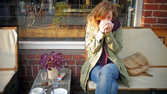 Eine junge Frau trinkt auf einer Bank sitzend in Kiel einen Kaffee. © NDR Foto: Maja Bahtijarevic