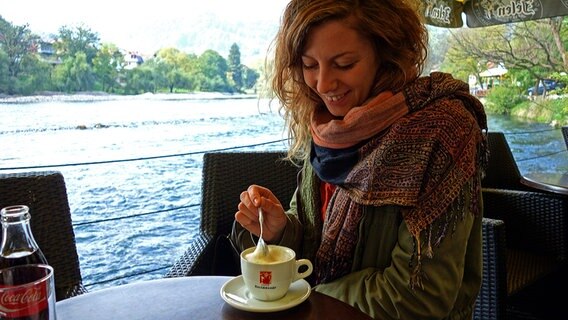 Eine junge Frau trinkt im Außenbereich eines Cafés im bosnischen Banja Luka einen Kaffee. © NDR Foto: Maja Bahtijarevic