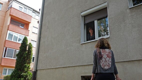 Eine junge Frau unterhält sich mit einer Bewohnerin, die durch ihr Fenster schaut im bosnischen Banja Luka. © NDR Foto: Maja Bahtijarevic