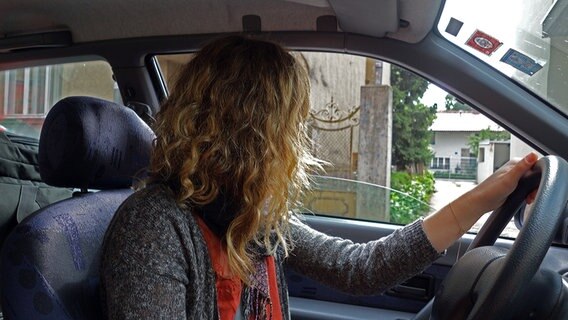 Eine junge Frau blickt aus dem Fenster ihres Autos in einen Hinterhof im bosnischen Banja Luka. © NDR Foto: Maja Bahtijarevic