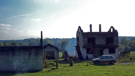 Zwei Männer stehen vor einer Ruine eines Wohnhauses in Bosnien © NDR Foto: Maja Bahtijarevic