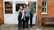 Susanne Gier steht mit ihrem Mann und ihren zwei Kindern vor der Eingangstür eines Hauses. © NDR Foto: Andrea Ring