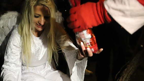 Engel Mandy verteilt gemeinsam mit dem Weihnachtsmann Geschenke an Kinder. © NDR Foto: Marina Heller