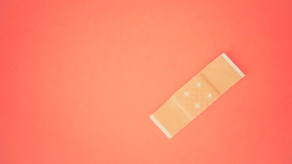 Ein Pflaster auf einer orangefarbenen Oberfläche. © Photocase Foto: EzraPortent