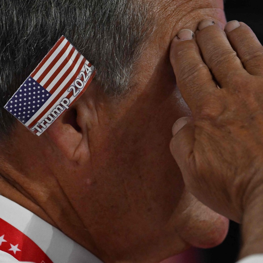 Trump Anhänger mit einem Patch der amerikanischen Flagge am Ohr auf dem Parteitag der Republikaner in  Milwaukee © AFP Foto: JIM WATSON