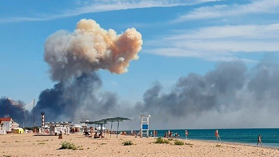 Am Strand von Saky auf der ukrainischen Halbinsel Krim ist Rauch nach einer Explosion am Horizont zu sehen. © AP/dpa 