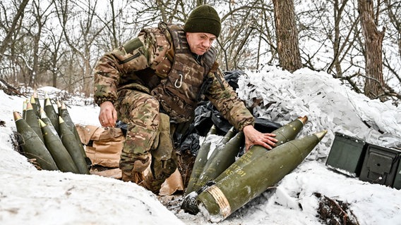 Ein Soldat der ukrainischen Streitkräfte steht nahe Saporischschja im Südosten der Ukraine neben Haubitzengranaten. © Ukrinform/dpa 