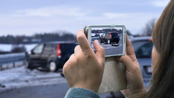 Eine Frau fotografiert mit ihrem Smartphone einen Unfall (Montage) Eine Frau fotografiert mit ihrem Smartphone einen Unfall (Montage) © Colourbox Foto: Giovanni, ThomasG