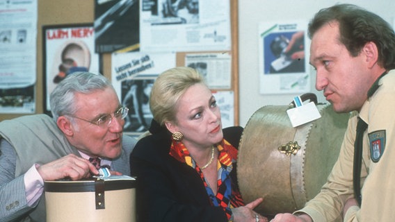 Können sie uns den gestohlenen Koffer wieder besorgen? Herr Linke (Edgar Bessen, l.) und Ehefrau (Barbara Schöne, M.) vertrauen auf Krügers (Peter Heinrich Brix, r.) ermittlungstechnische Fähigkeiten. © NDR/ARD/Isa Foto: Walther