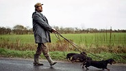 Schauspieler Bjarne Mädel geht mit drei Dackeln an der Leine spazieren. © NDR 