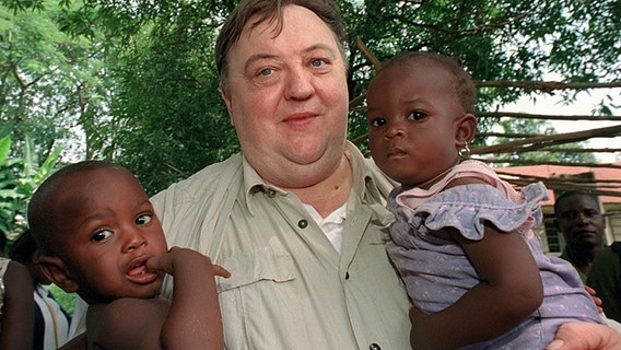 Zwei Babys von vergewaltigten Kindersoldatinnen hält der deutsche Schauspieler Dieter Pfaff am 21.10.2002 in Makeni in Sierra Leone im Arm. Pfaff ist Pate des Kinderhilfswerk der Vereinten Nationen UNICEF. © dpa-Fotoreport 