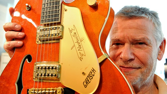 Der Musiker Achim Reichel blickt am 08.10.2010 in Hamburg in seinem Tonstudio hinter einer seiner 25 Gitarren hervor. © (c) dpa 