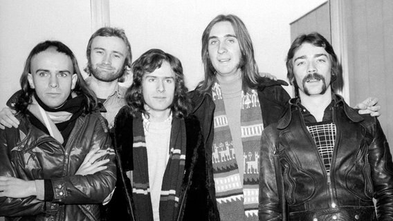 Die Band Genesis am 28. Februar 1974 am Flughafen London-Heathrow. Von links nach rechts: Sänger Peter Gabriel, Drummer Phil Collins, Keyboarder Tony Banks, Bassist Mike Rutherford, Gitarrist Steve Hackett. © picture alliance / empics 