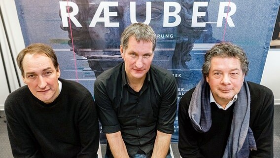 Reimer Bustorff (l-r), Musiker der Band Kettcar, Marcus Wiebusch, Musiker der Band Kettcar, und Daniel Karasek, Generalintendant des Schauspiels Kiel, posieren am 11.01.2016 in Kiel (Schleswig-Holstein) vor dem Plakat zur Inszenierung "Die Räuber". © dpa-Bildfunk Foto: Markus Scholz