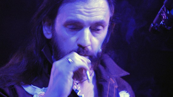 Der Sänger und Bassist der britischen Rock-Band Motörhead, Lemmy Kilmister, steht am 16. Oktober 2005 rauchend auf der Bühne des CCH. © picture-alliance / jazzarchiv 