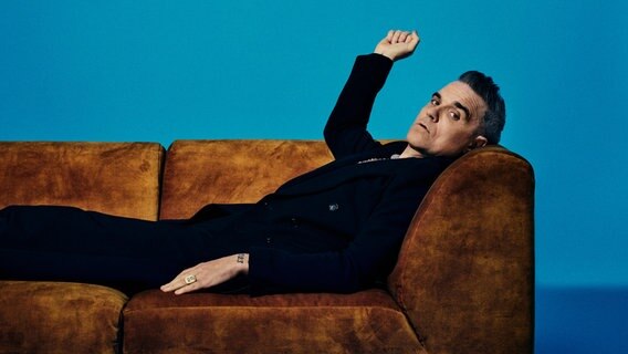 Robbie Williams liegt auf einem Sofa und schaut in die Kamera © MCT Agentur GmbH, Netflix Foto: MCT Agentur GmbH, Netflix