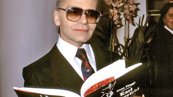 Karl Lagerfeld hält ein Buch in den Händen (Aufnahme vom 12. November 1986) © Picture-Alliance / Photoshot 