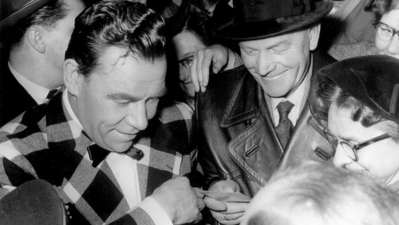 Der beliebte deutsche Showmaster Peter Frankenfeld wurde in den 50er-Jahren mit karierter Jacke und durch seine Sendung "1:0 für Sie" (hier gibt er nach der Sendung Autogramme) einem breiten Publikum bekannt. © dpa-Bildarchiv 