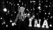Ina Müller tanzt im Video zu "Wenn ich wegguck" zwischen an Kabeln herunter hängenden Glühbirnen. © NDR 