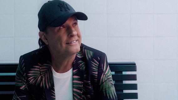 Peter Schilling sitzt auf einer Bank und lächelt © WMG 