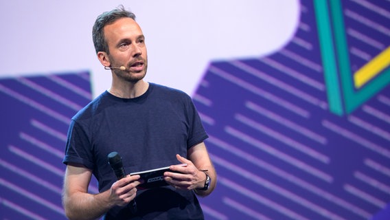 Philipp Westermeyer hat eine Pappkarte in der Hand und spricht in ein Mikrophon © Picture Alliance Foto: Jonas Walzberg