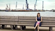 Anneke Kim Sarnau sitzt auf einer Bank am Hamburger Hafen. © NDR 