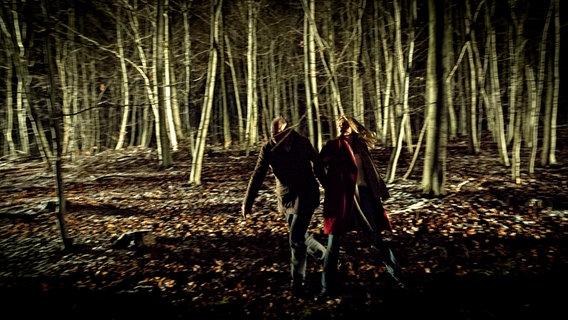 Klaus Borowski (Axel Milberg, li.) und Charlotte Lindholm (Maria Furtwängler, re.) fliehen durch einen Wald vor dem Entführer. © © NDR/Meyerbroeker 