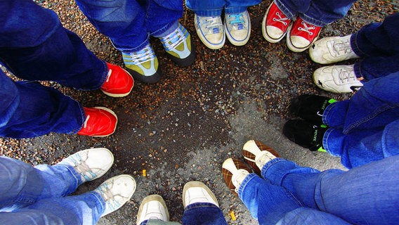 Eine Gruppe von Menschen steht im Kreis. Man sieht die Füße und die Beine der Gruppe. © photocase.de Foto: FräuleinC