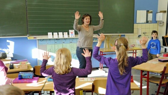 Eine Lehrerin unterrichtet eine Klasse von Grundschülern. © Imago/Becker & Bredel 