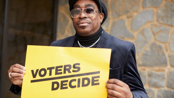 ein Wähler hält ein  gelbes Plakat hoch in Milwaukee, Wisconsin, USA © Reuters Foto: Daniel Steinle