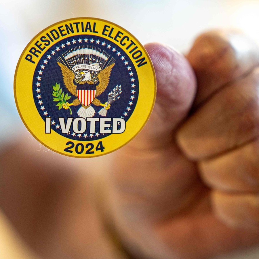 Early In-Person Voting Starts In Virginia, eine Hand hält einen Aufkleber mit der Aufschrift: Presidential Election I Voted 2024 © AFP Foto: ANDREW HARNIK