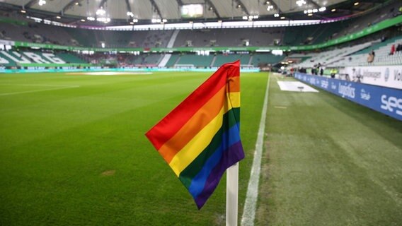 Regenbogenfahne liegt auf Stadionrasen © IMAGO / regios24 