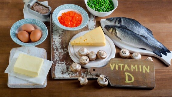 Butter, Eier, Fisch, Erbsen, Käse, Champignons, Fisch in der Dose, orangefarbene Kügelchen auf einem Teller und ein Holzbrett auf dem Vitamin D steht. © fotolia.com Foto: bit24