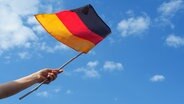 Eine Deutschlandflagge weht vor blauem Himmel. © fotolia.com Foto: Andreas Berheide