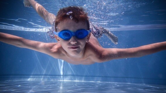 Ein Kind mit blauer Taucherbrille unter Wasser. © photocase.de Foto: jockelo