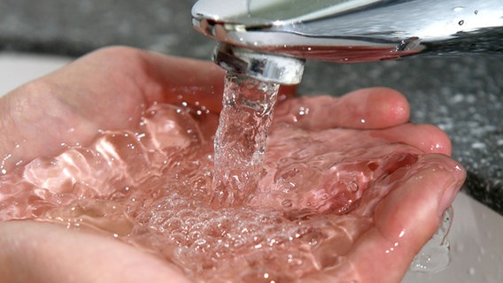 Aus einem Wasserhahn fließt Wasser in zwei Hände © dpa 