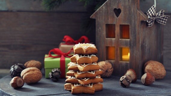 Weihnachtskekse und Nüsse liegen gestapelt vor einem Windlicht aus Holz. © Colourbox Foto: Tetiana Vitsenko