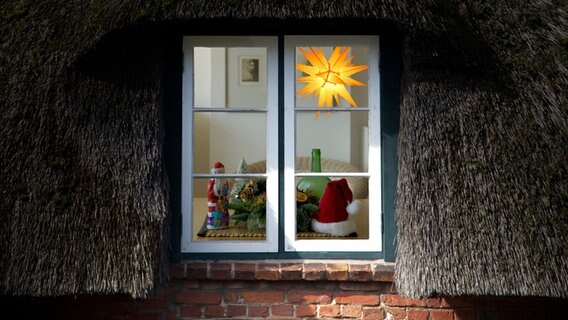 Blick in das Fenster eines reetgedeckten Hauses mit weihnachtlicher Dekoration © photocase.de Foto: MacRein
