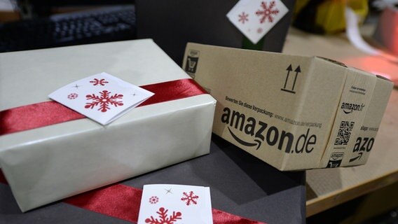 Weihnachtspakete liegen in einem Amazon-Logistikzentrum auf einem Packtisch. © picture alliance / dpa | Hendrik Schmidt 