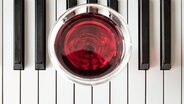 Ein Glas Rotwein auf den Tsten eines Klaviers. © panthermedia/tosirikul Foto: tosirikul