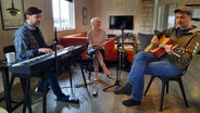 Die drei Musiker der Band Godewind sitzen zusammen und musizieren. © NDR Foto: Lina Bande