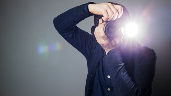 Mann blitzt mit einer Kamera den Fotofrafen an. © fotolia Foto: Victor Koldunov