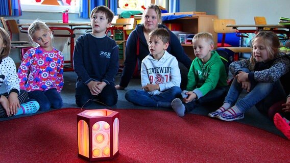 Die Kindern der ersten Klasse der Knüttel-Antonius-Schule sitzen um eine Laterne © NDR Foto: Rebekka Merholz