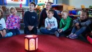 Die Kindern der ersten Klasse der Knüttel-Antonius-Schule sitzen um eine Laterne © NDR Foto: Rebekka Merholz