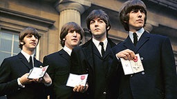 Die Beatles, (l-r) Ringo Starr, John Lennon, Paul McCartney und George Harrison, präsentieren einen Orden der englischen Königin. © dpa - Report 